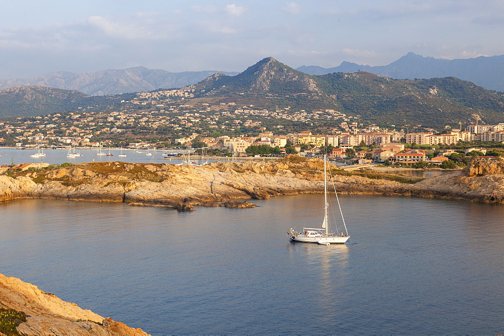 A sail boat in the clear sea around the village of Ile Rousse at sunset, Balagne Region, Corsica, France, Mediterranean, Europe