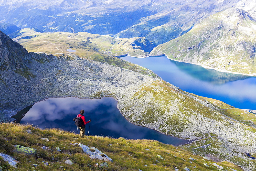 Hiker on the shore of Lago Nero admires the blue Lake Montespluga in summer, Chiavenna Valley, Valtellina, Lombardy, Italy, Europe