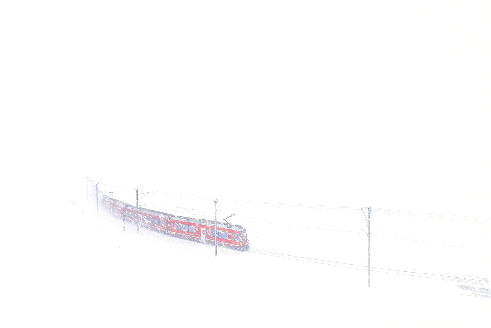 Bernina Express train at Bernina Pass during a snowstorm, Engadine, Canton of Graubunden, Switzerland, Europe