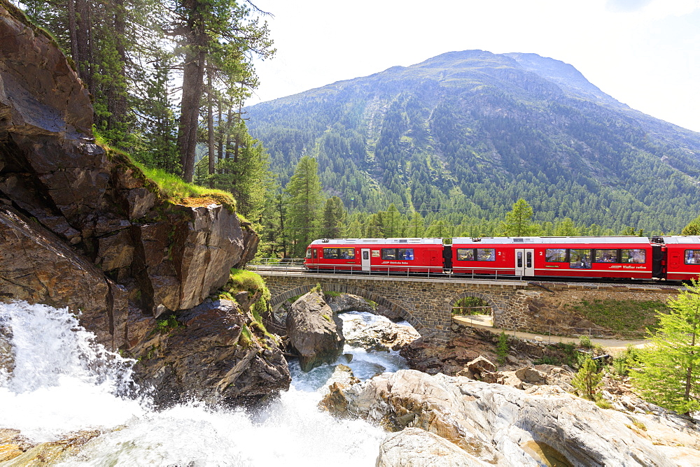 Bernina Express train beside alpine creek, Morteratsch, Engadine, Canton of Graubunden, Switzerland, Europe