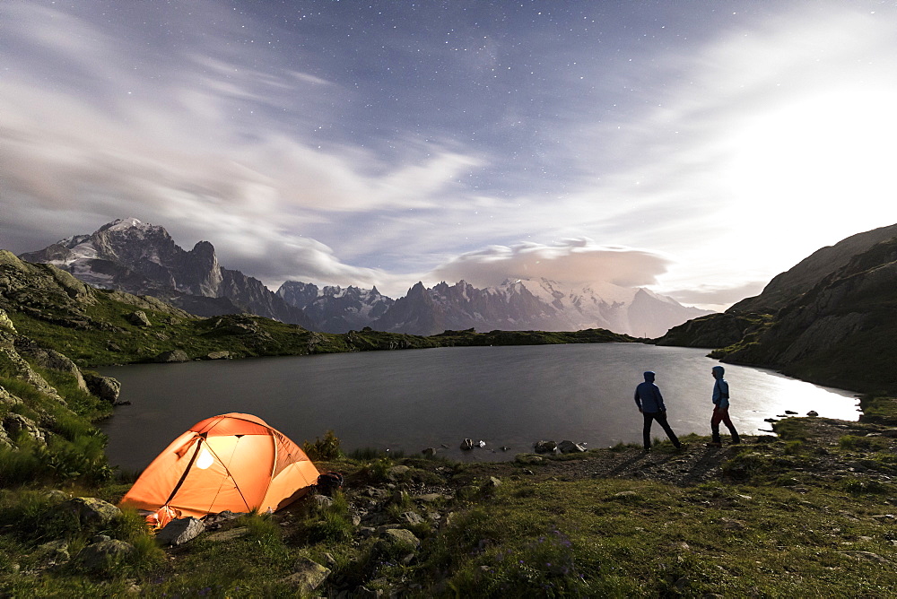 Hikers and tent on the shore of Lacs De Cheserys at night with Mont Blanc massif in the background, Chamonix, Haute Savoie, French Alps, France, Europe