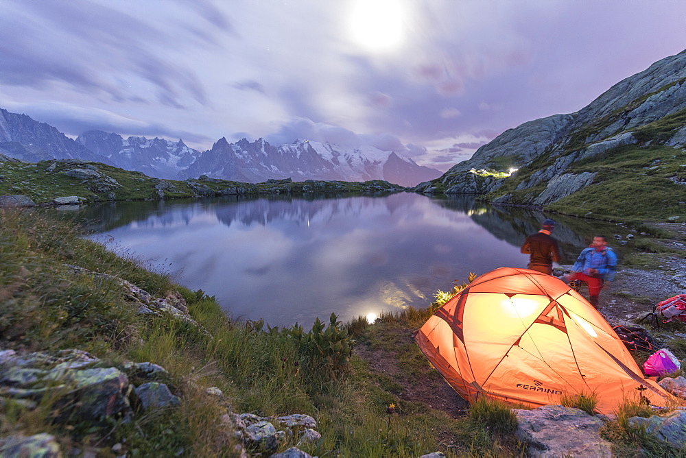 Hikers and tent on the shore of Lacs De Cheserys at night with Mont Blanc massif in background, Chamonix, Haute Savoie, French Alps, France, Europe