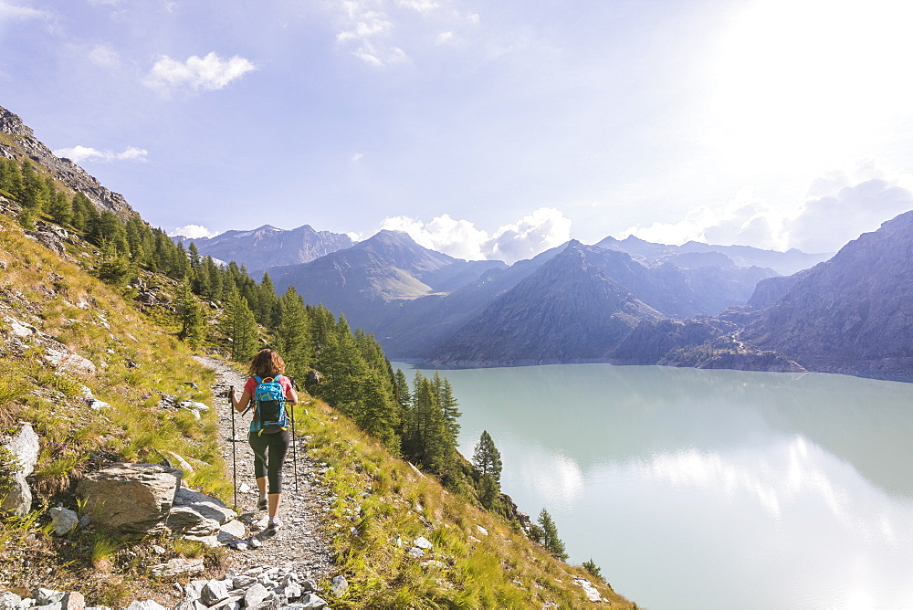 Hiker on path towards Rifugio Bignami beside the dam and water basin of Alpe Gera, Malenco Valley, Valtellina, Lombardy, Italy, Europe