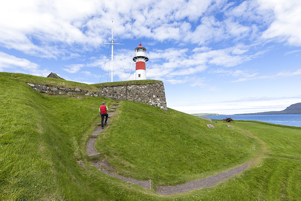 Man walks to the lighthouse and historic fortress of Skansin,Torshavn, Streymoy Island, Faroe Islands, Denmark, Europe