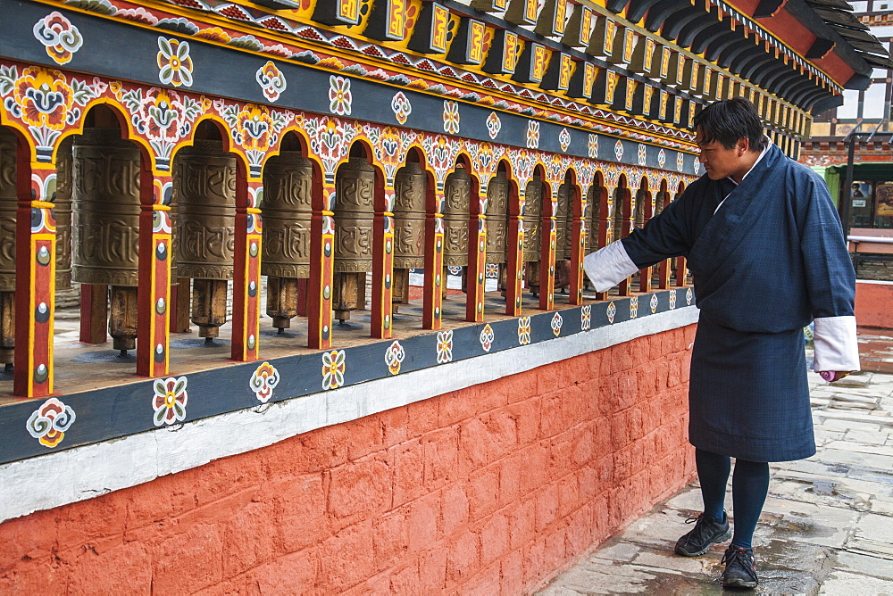 A man rotates the roller-books of the Monastery of Rinpung Dzong which are used to pray, Paro, Bhutan, Asia