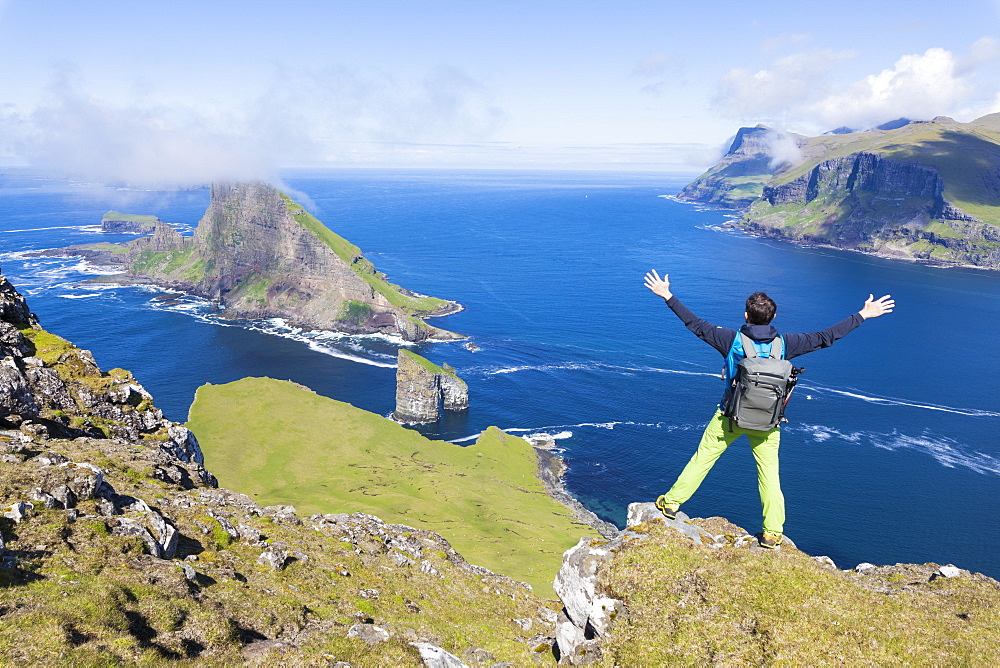 Man on cliffs looks towards Drangarnir rock, Vagar Island, Faroe Island, Denmark, Europe