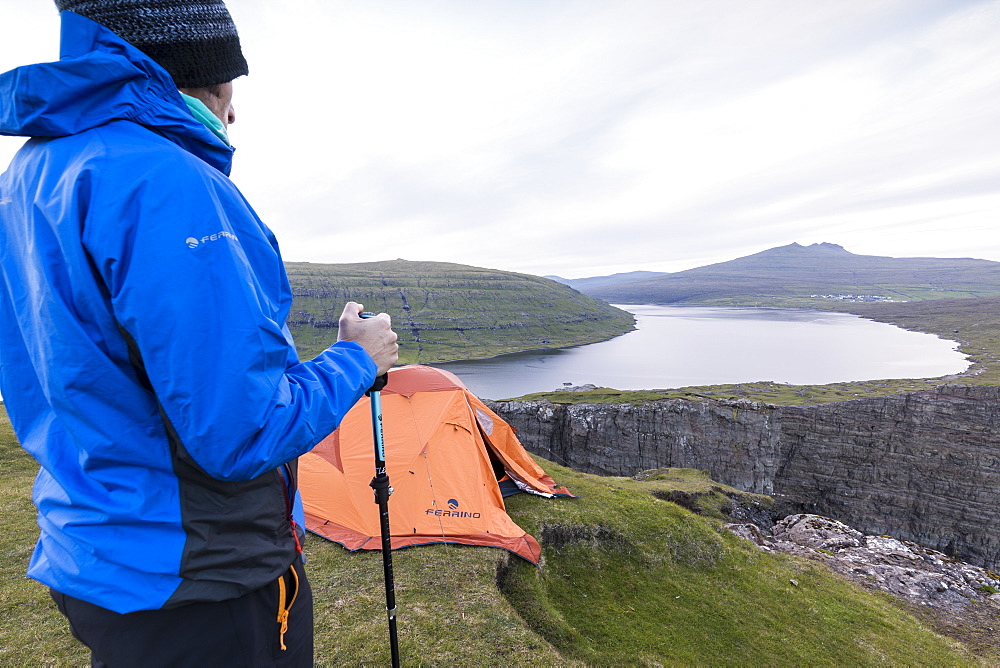 Hiker on cliffs looks towards lake Sorvagsvatn, Vagar Island, Faroe Islands, Denmark, Europe