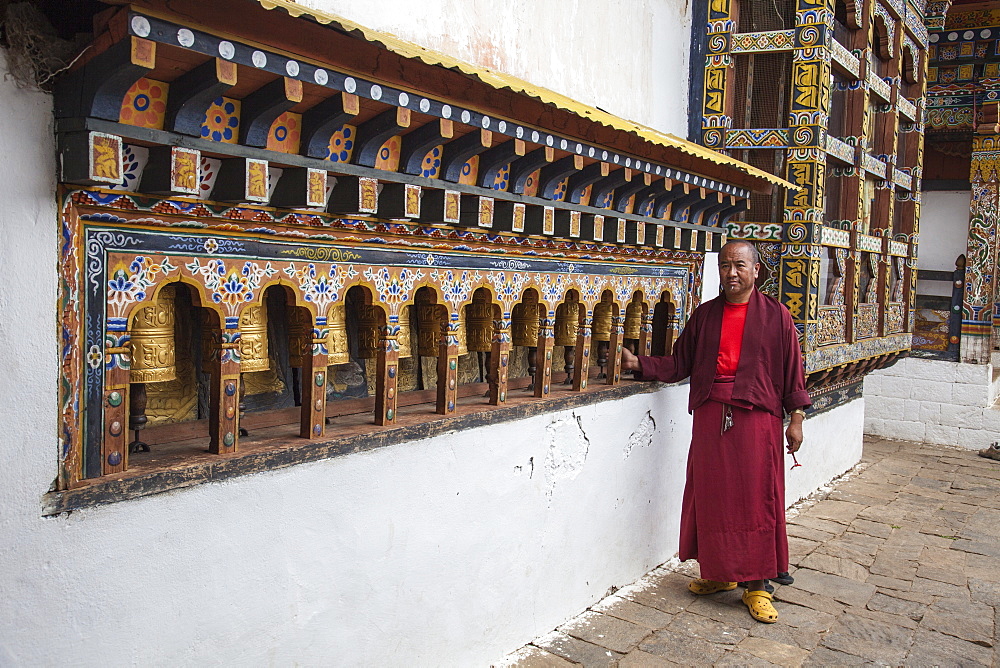 A monk rotates the roller-books of the Monastery of Punakha Dzong which are used to pray, Paro, Bhutan, Asia