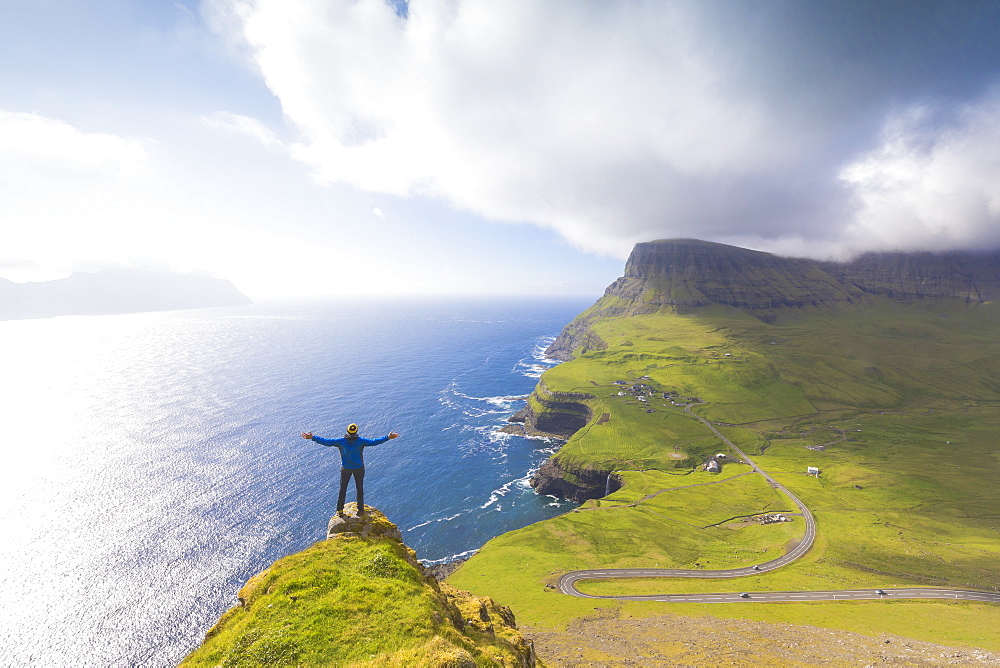 Hiker on top of rocks, Gasadalur, Vagar Island, Faroe Islands, Denmark, Europe