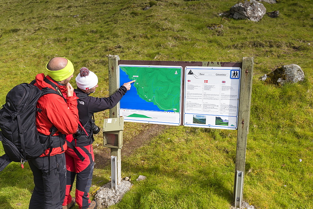 Hikers looking at maps, Gasadalur, Vagar Island, Faroe Islands, Denmark, Europe