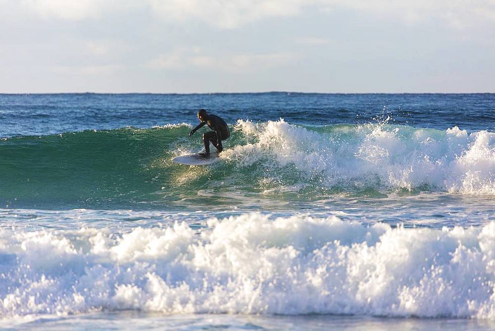 Surfer rides waves, Unstad, Vestvagoy, Lofoten Islands, Nordland, Norway, Europe