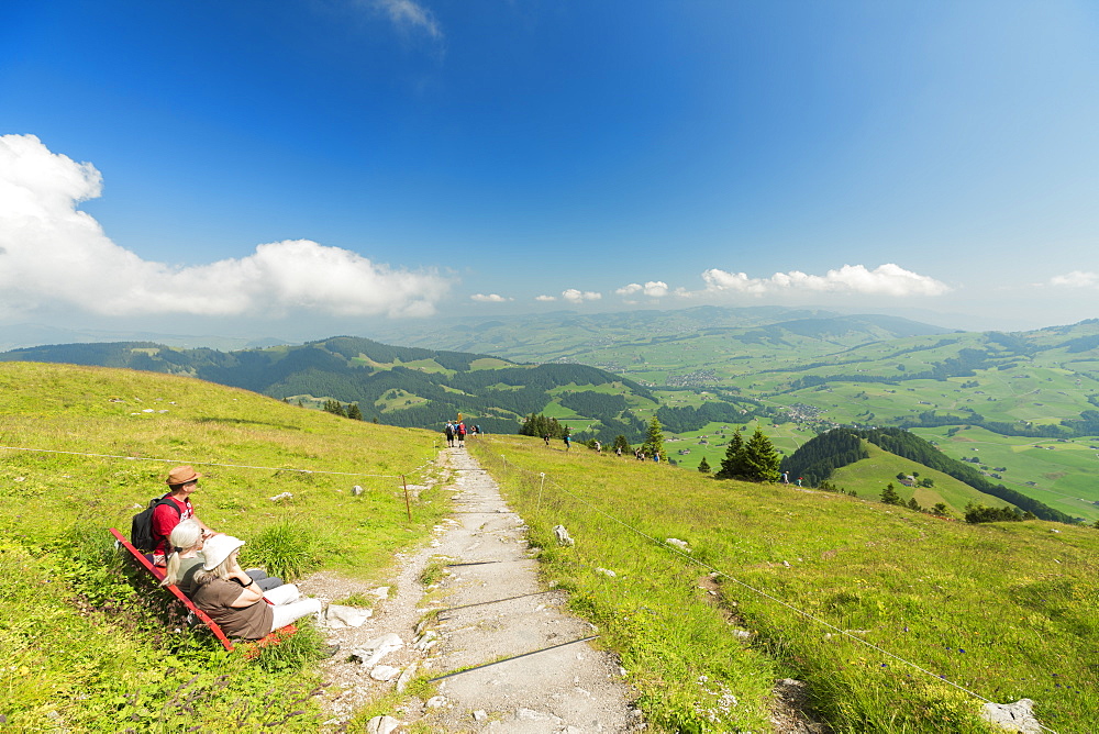 People on bench in the green valley of Ebenalp looking towards Appenzell and Schwende, Appenzell Innerrhoden, Switzerland, Europe