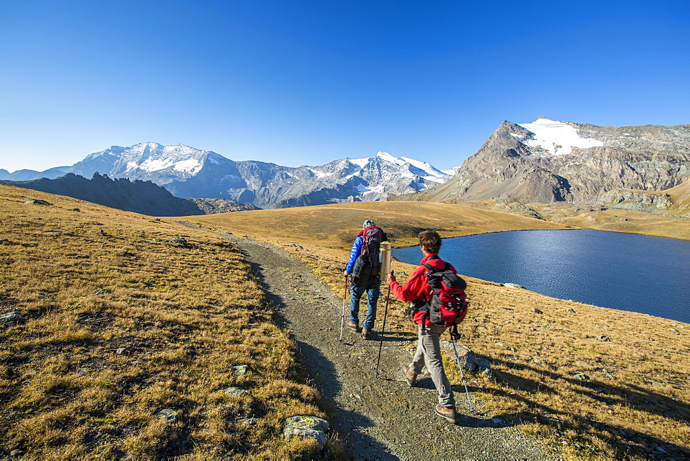 Hikers wallking along Rosset Lake, Gran Paradiso National Park, Alpi Graie (Graian Alps), Italy, Europe