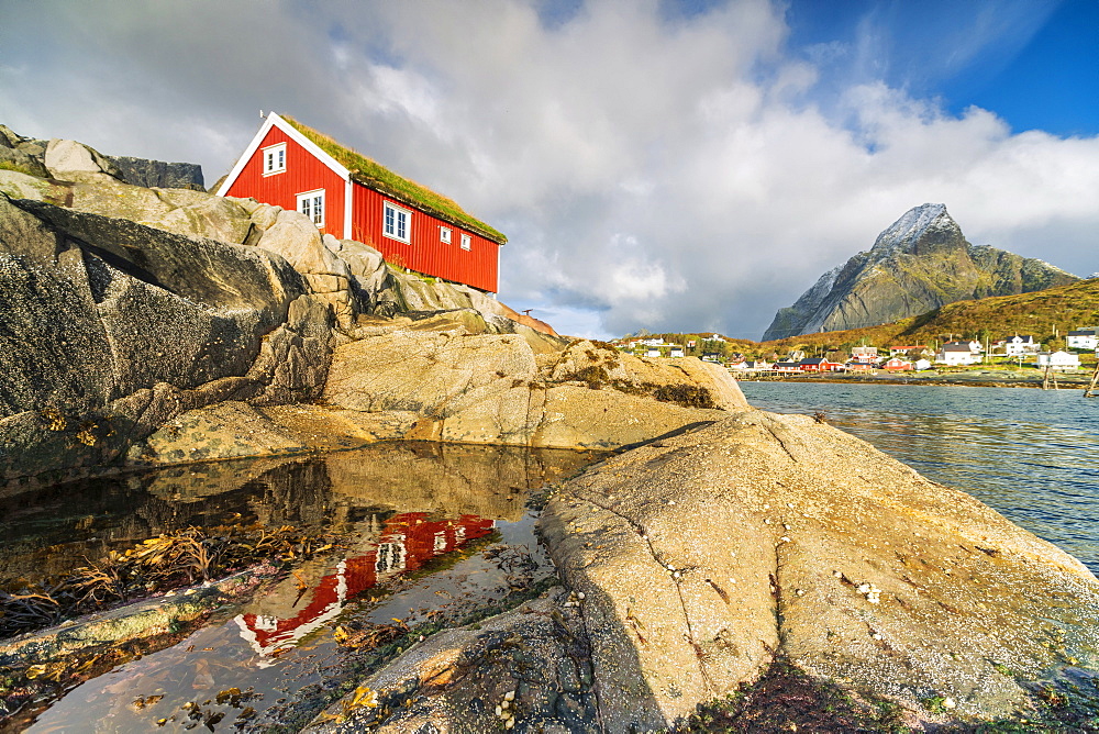 Red cabin by seaside rocks in Reine, Moskenes, Nordland, Lofoten Islands, Norway, Europe