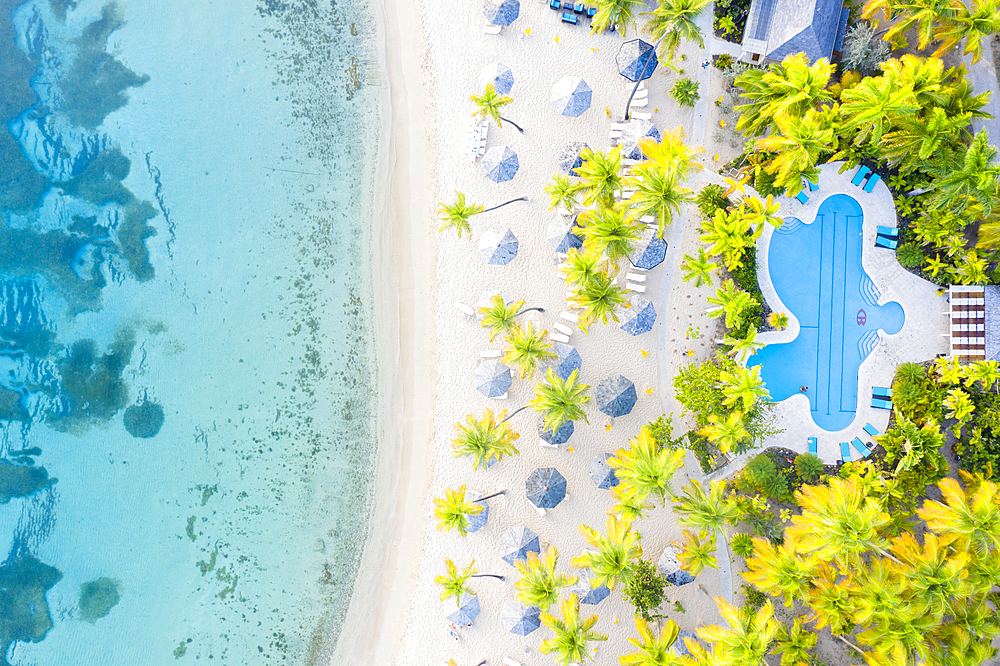 Swimming pool and beach umbrellas on white sand beach from above by drone, Morris Bay, Old Road, Antigua, Leeward Islands, West Indies, Caribbean, Central America