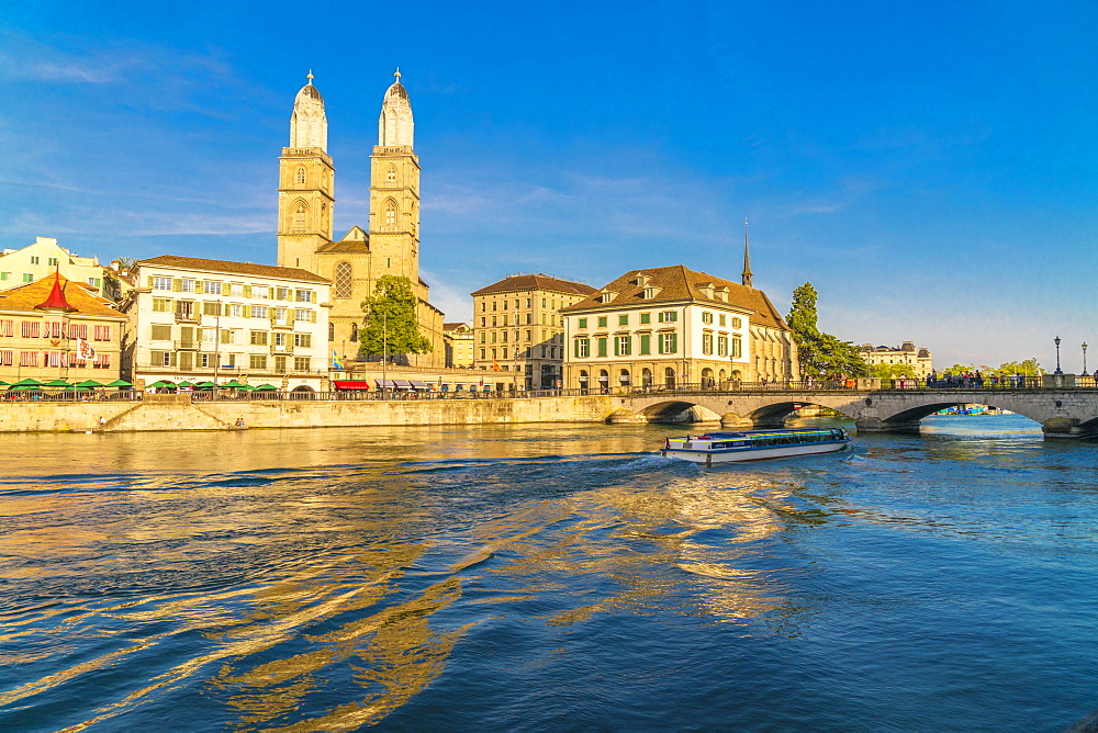 Ferry along Limmat River next to Munsterbrucke bridge with Grossmunster in background, Zurich, Switzerland, Europe