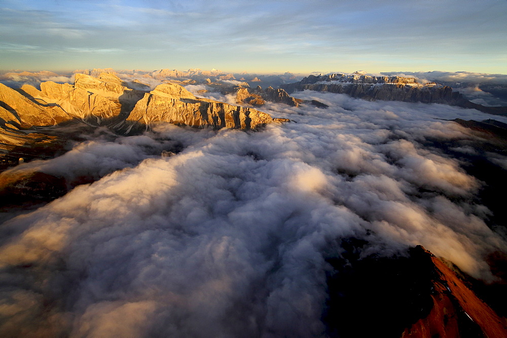 Aerial shot of Sella Group Alps surrounded by clouds at sunset in the Dolomites, Val Funes, Trentino-Alto Adige South Tyrol, Italy, Europe