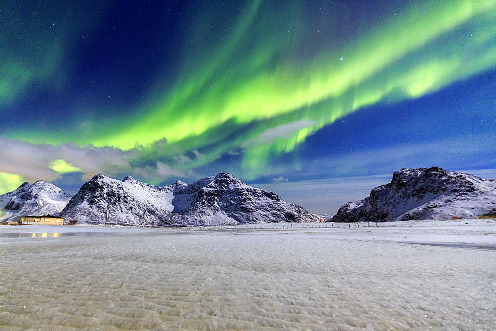 Northern Lights (aurora borealis) illuminate the sky and the snowy peaks, Flakstad, Lofoten Islands, Arctic, Norway, Scandinavia, Europe