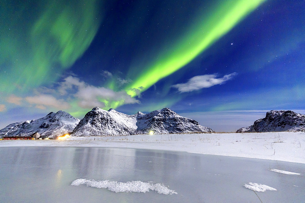 Northern Lights (aurora borealis) illuminate the sky and the snowy peaks, Flakstad, Lofoten Islands, Arctic, Norway, Scandinavia, Europe