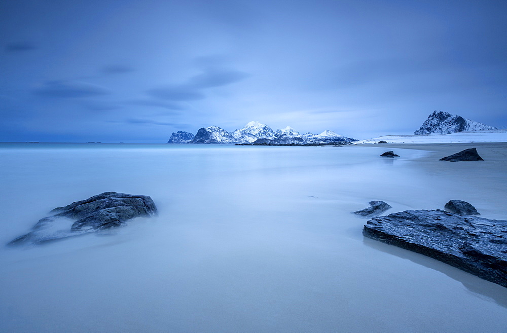 The cold blue sea bathes the beach still partially snowy. Myrland, Lofoten Islands, Northern Norway, Scandinavia, Arctic, Europe