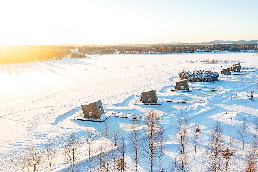 Wooden cabins rooms of the luxury Arctic Bath Spa Hotel floating on frozen river Lule covered with snow, Harads, Lapland, Sweden