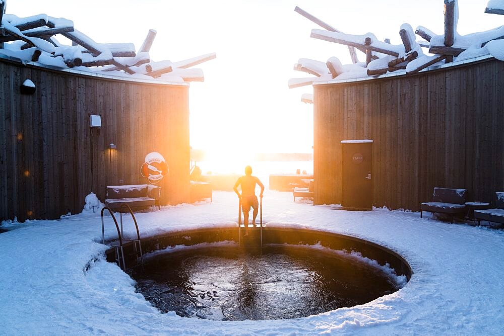 Person enjoying the open-air cold baths in the circular pool of the Arctic Bath Spa Hotel, Harads, Lapland, Sweden