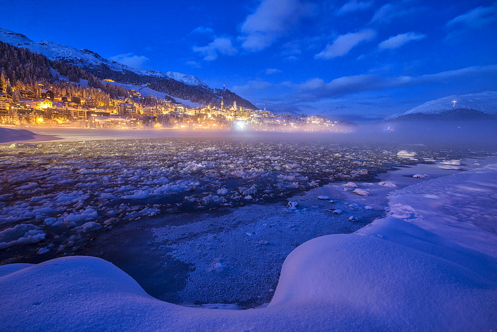 The frozen Inn river and the village of Sankt Moritz at dusk, Engadine, Canton of Grisons (Graubunden), Switzerland, Europe