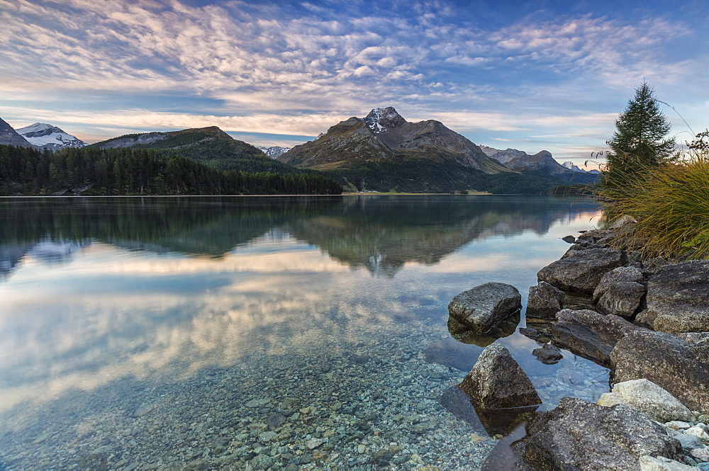 Pink sky at dawn illuminates the peaks reflected in Lake Sils, Engadine, Canton of Graubunden, Switzerland, Europe