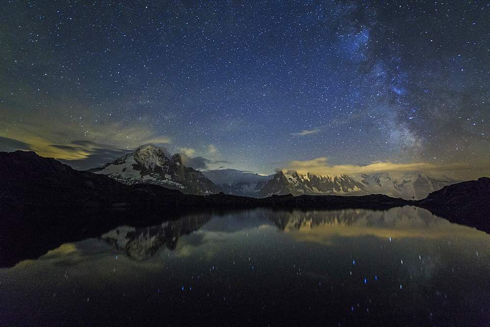 Stars and Milky Way illuminate the snowy peaks and Lac de Cheserys, Chamonix, Haute Savoie, French Alps, France, Europe