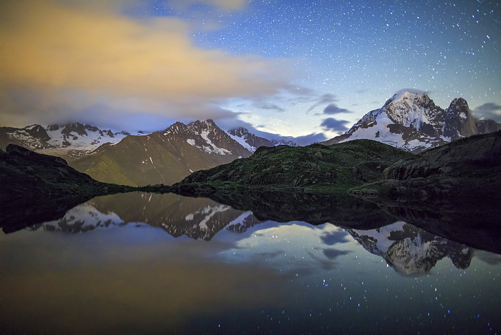 The stars illuminate the snowy peaks and reflected in Lac de Cheserys, Chamonix, Haute Savoie, French Alps, France, Europe