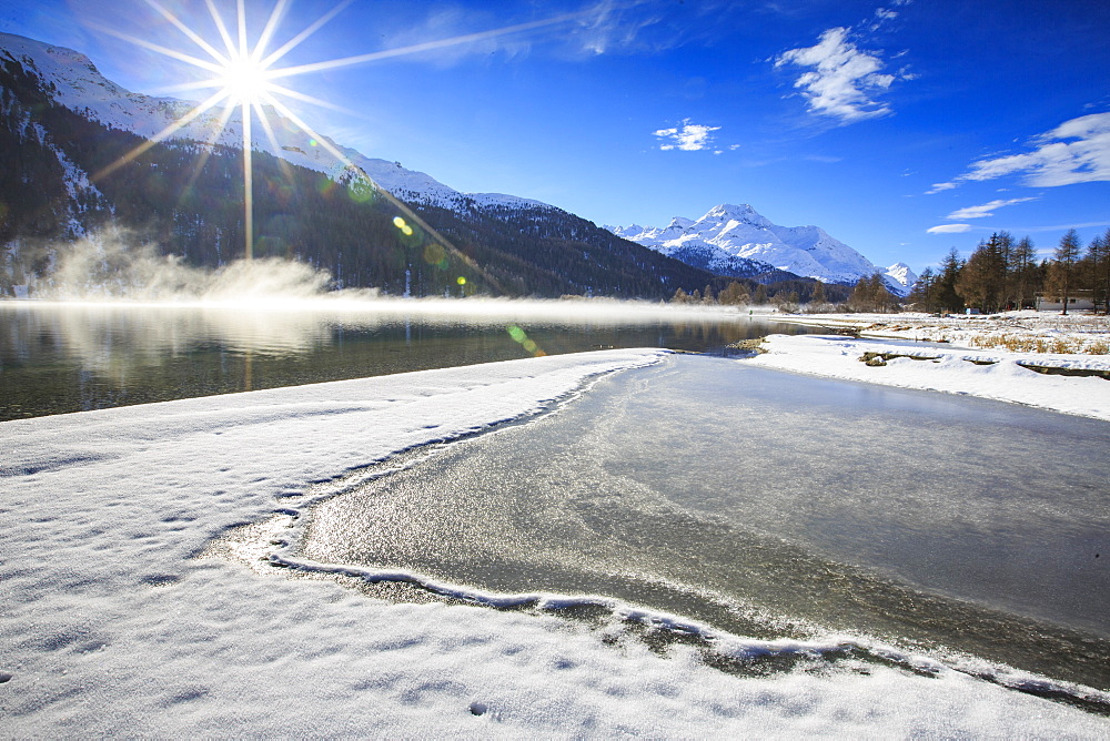 Rays of winter sun illuminate Lake Silvaplana still partially frozen, Maloja, Engadine, Graubunden Canton, Switzerland, Europe