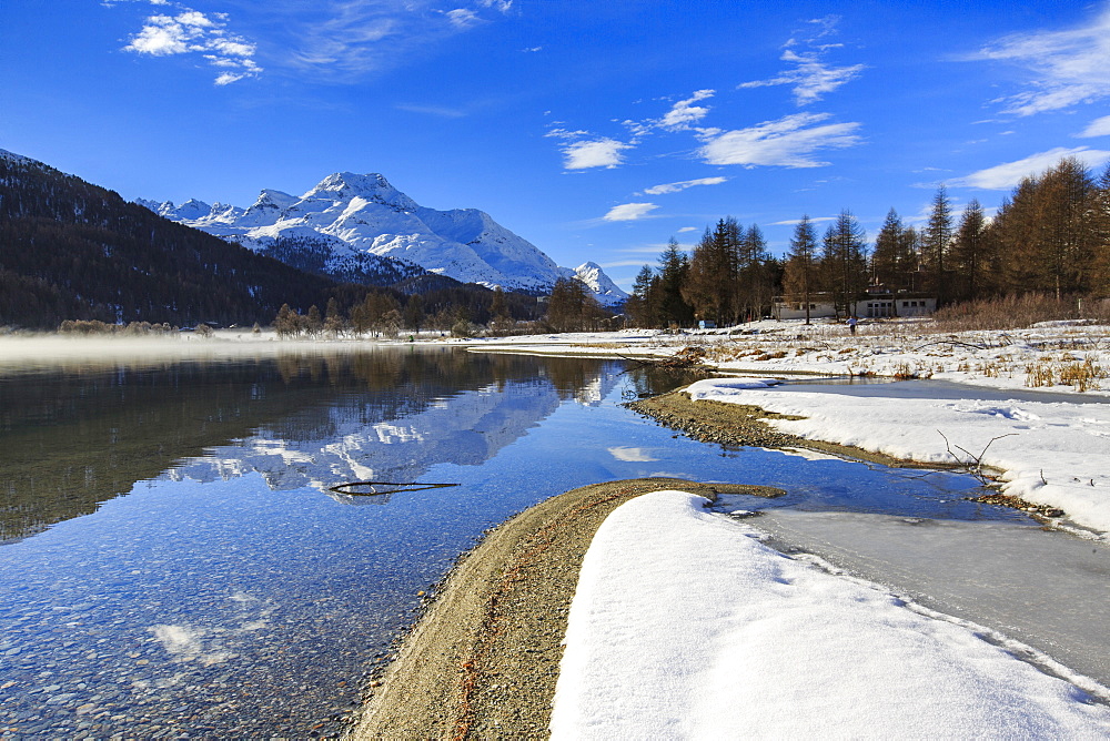 Snowy peaks are reflected in Lake Silvaplana still partially frozen, Maloja, Canton of Graubunden, Engadine, Switzerland, Europe