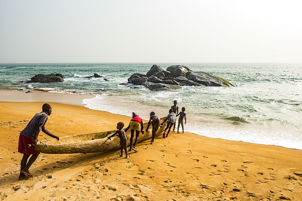 Locals pushing a canoe in the ocean east of Buchanan, Liberia, West Africa, Africa