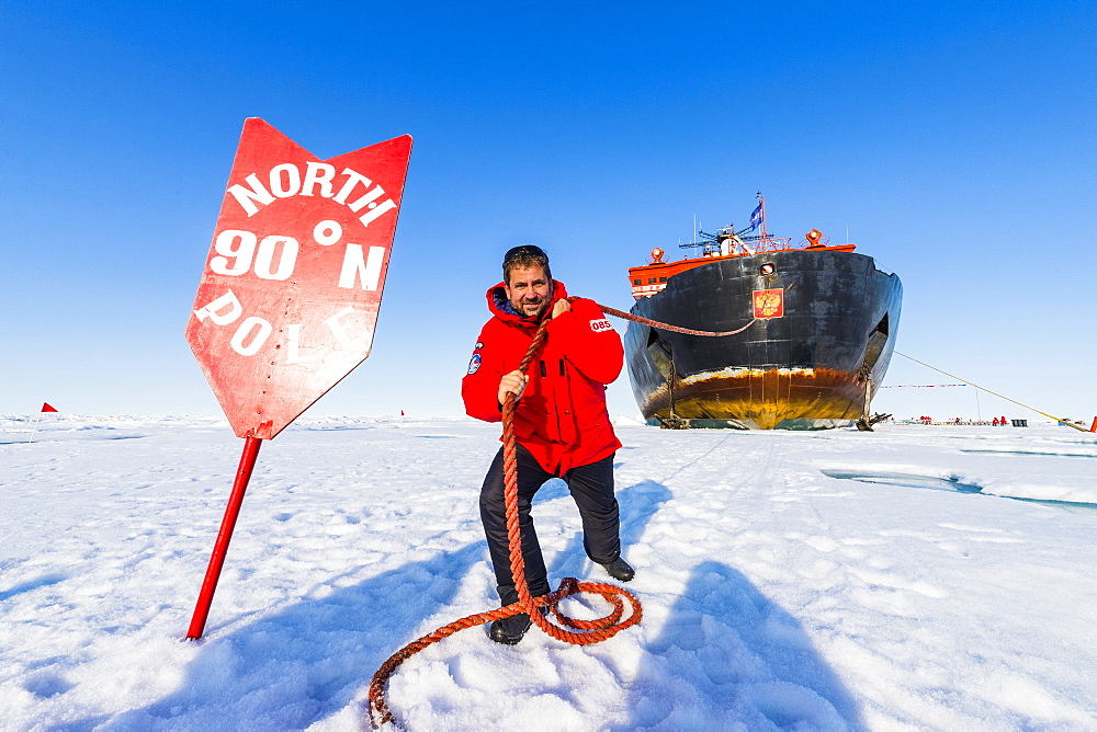 Man pretending to pull the Icebreaker '50 years of victory' on the North Pole, Arctic