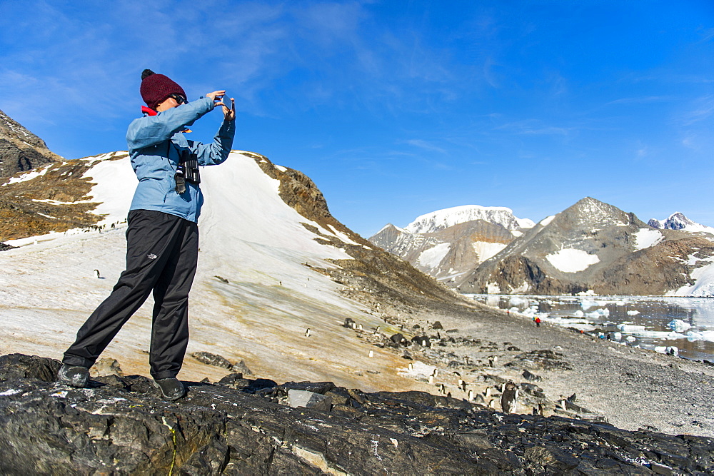 Tourist photographing the beautiful bay filled with icebergs in Hope Bay, Antarctica, Polar Regions