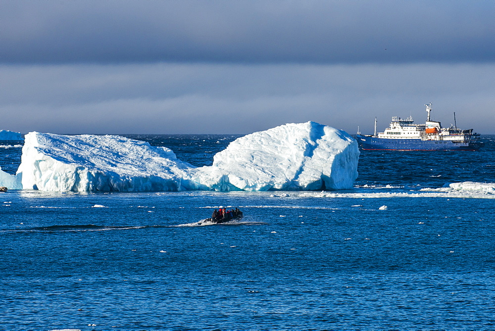 Zodiac cruising back to a cruise ship anchoring behind an iceberg, Brown Bluff, Antarctica, Polar Regions