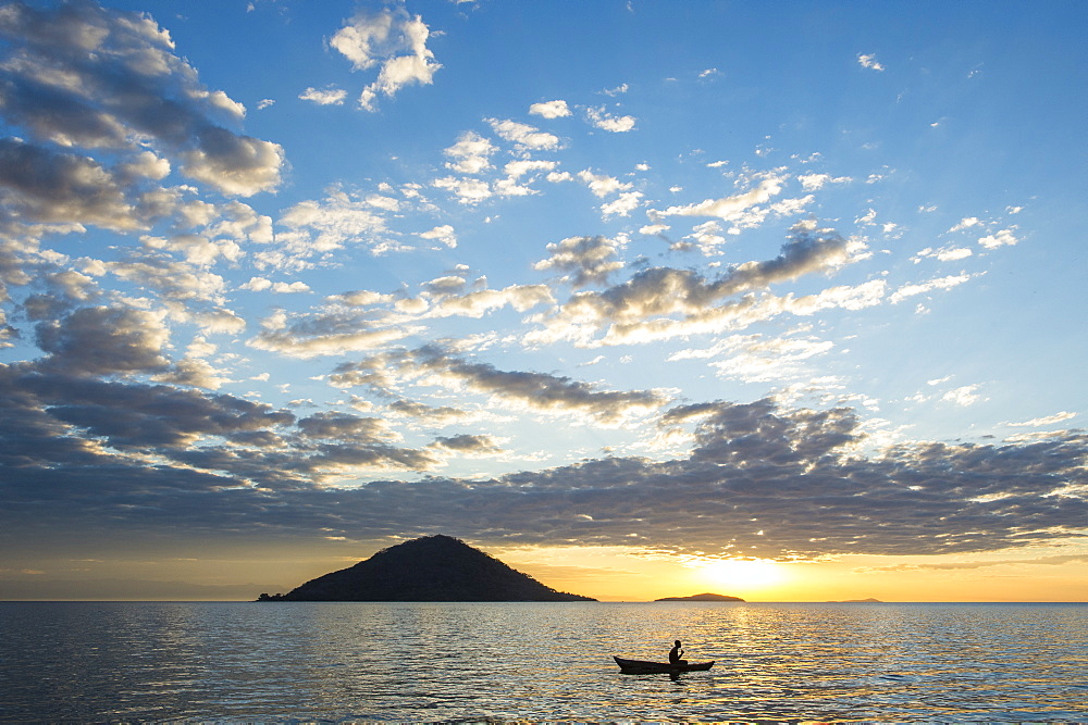 Silhouette of a man in a little fishing boat at sunset, Cape Malcear, Lake Malawi, Malawi, Africa