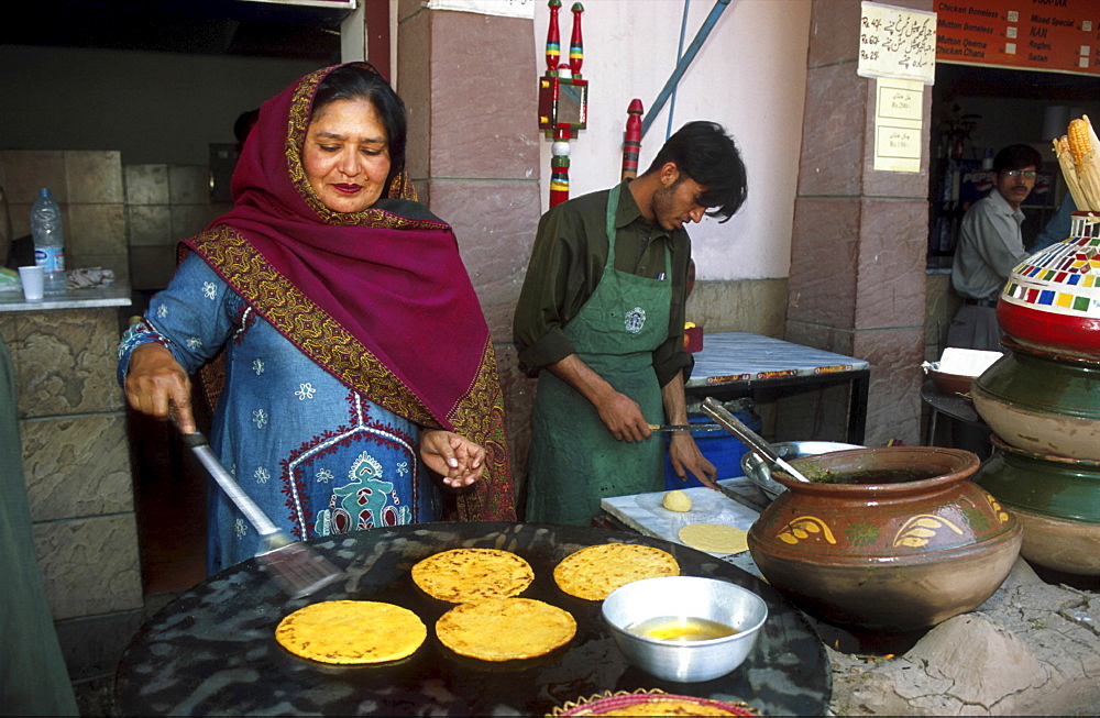 Street kitchen, pakistan. Making pokharas (fried chappatis) at a food stall