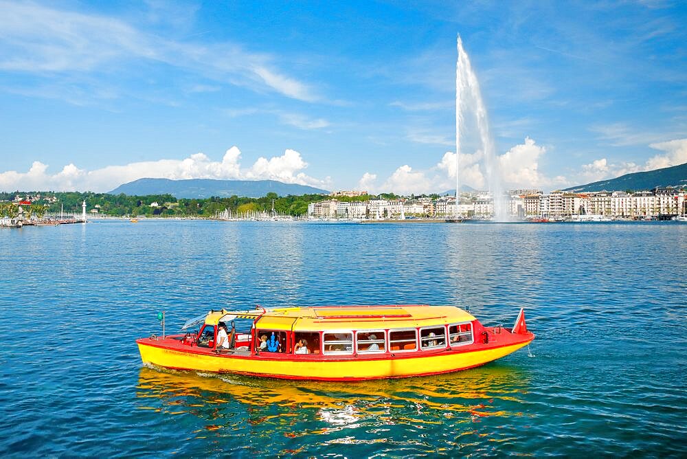 Yellow water taxi ???Mouettes genevoises??? on the calm waters of Lake Geneva with tourist attraction Jet d'eau in the background