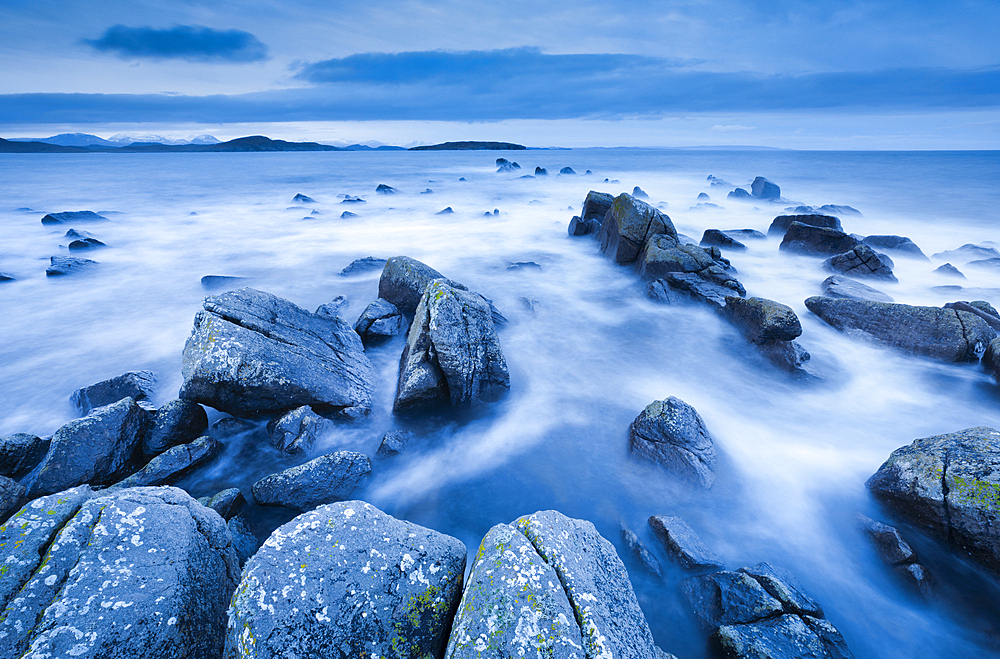 Rocks and Summer Isles in the background during dramatic blue lighting at dusk on the shores of northwest Scotland, Highland, Scotland, United Kingdom, Europe