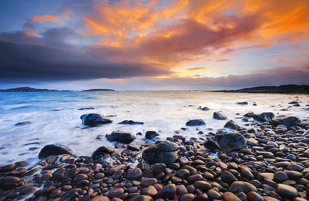 Stone beach at Reiff Bay with the Summer Isles in the background during colourful sunset on the shores of northwest Scotland, Highland, Scotland, United Kingdom, Europe