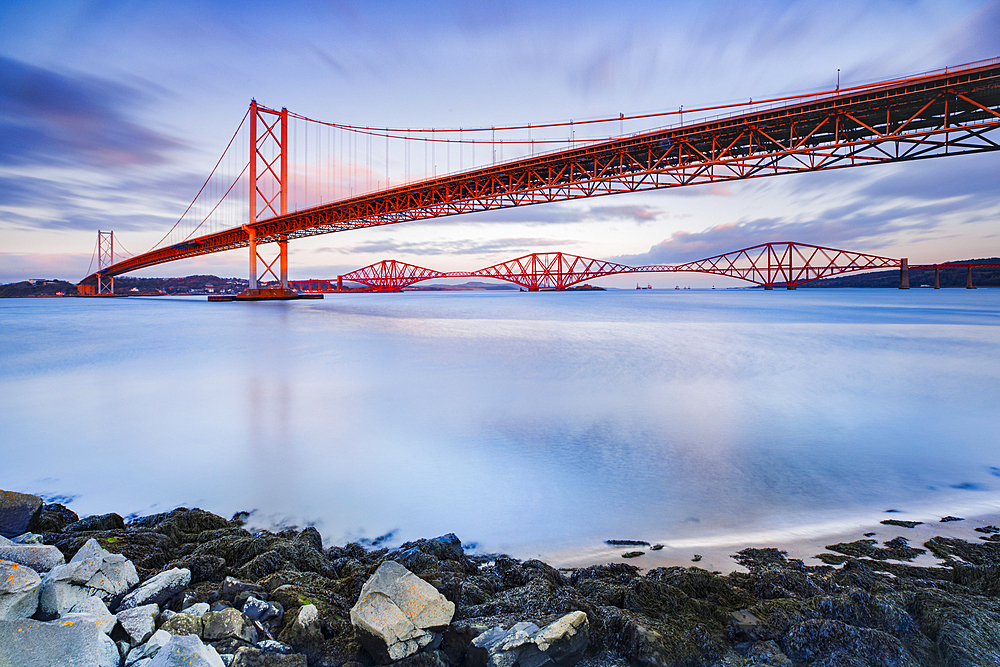 Forth Road Bridge and the red Forth Bridge railway crossing, UNESCO World Heritage Site, beyond, lit by evening light, view from the Fírth of Forth in South Queensferry, near Edinburgh, Scotland, United Kingdom, Europe