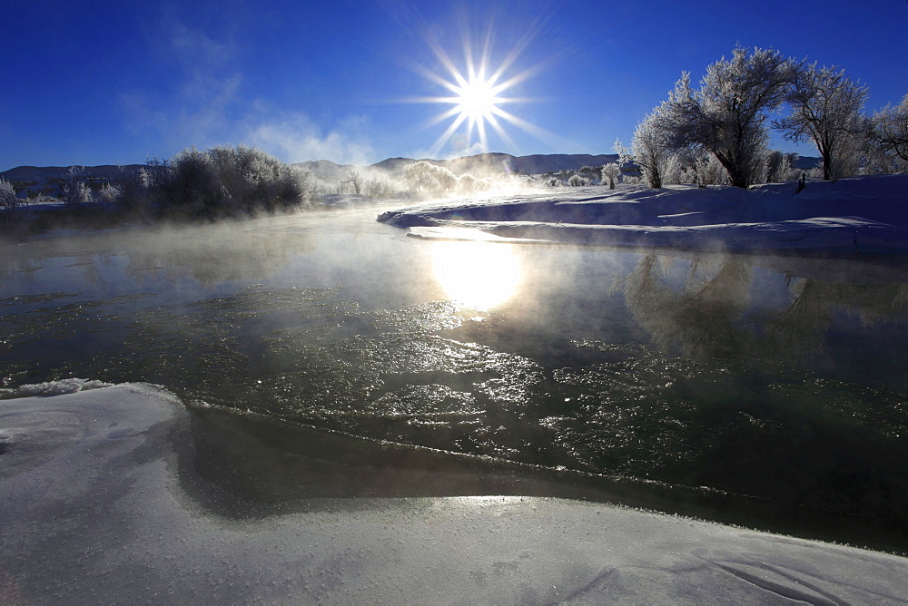 Winter landscape with hoarfrost, steeming river, brilliant sunshine and blue sky, utah, usa