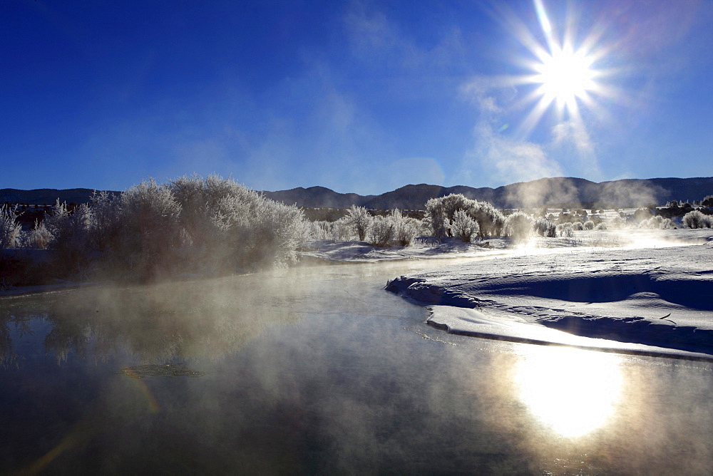 Winter landscape with hoarfrost, steeming river, brilliant sunshine and blue sky, utah, usa