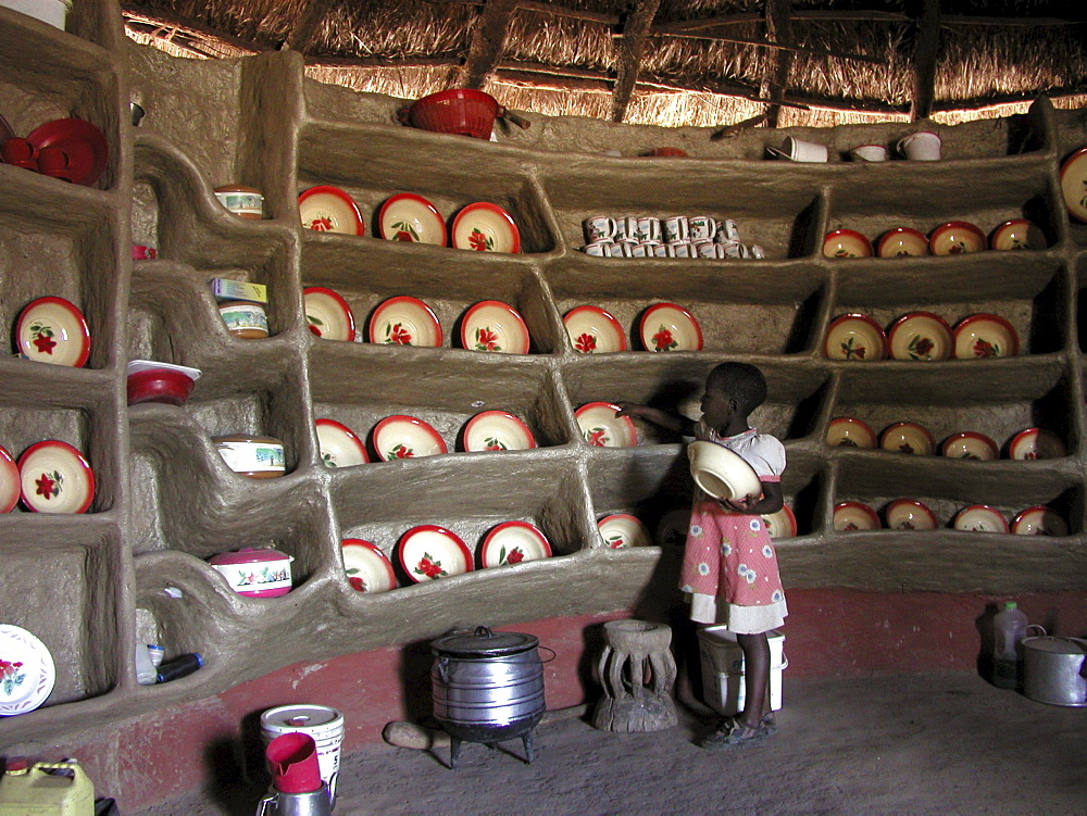 Zambia 7-year-old constance mabo of chikwela village, chongwe, puting away dishes in her grandmothers kitchen