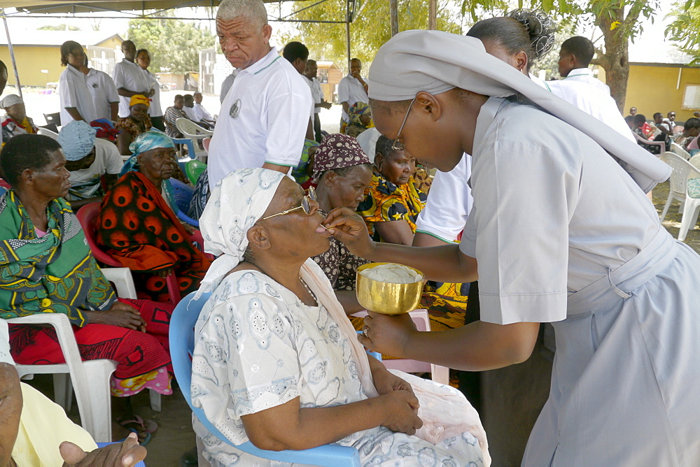 TANZANIA The Roman Catholic Parish of Buza, Dar es Salaam. Sunday mass. Nun giving sacrament to the sick sitting outside church. photograph by Sean Sprague