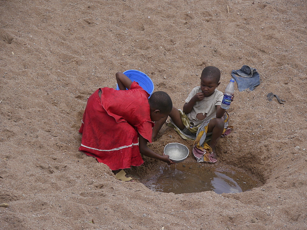 TANZANIA Children collecting water from a dried up river bed near Shinyanga. photograph by Sean Sprague