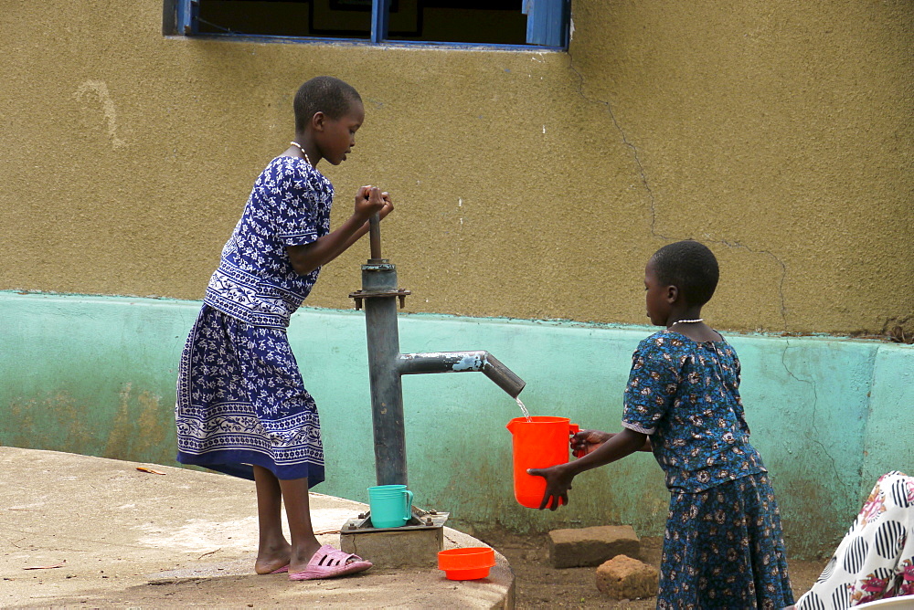 TANZANIA Home of Compassion, for the sick and needy, Kigera village, near Musoma. Girls collecting water from hand pump. photograph by Sean Sprague