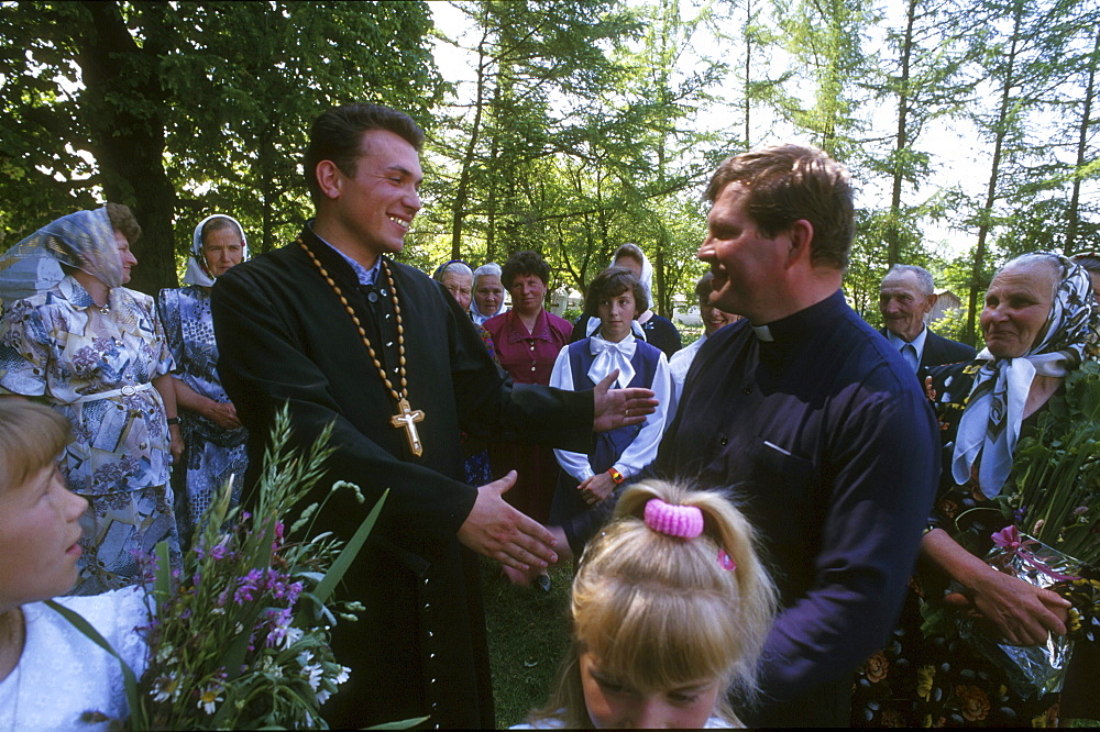 Ukraine orthodox and catholic priest, who share the church builing at different shifts, greet other. Zolochov