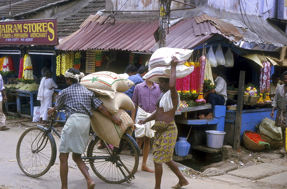 India - transportation carrying sacks of in a market street trivandrum, kerala